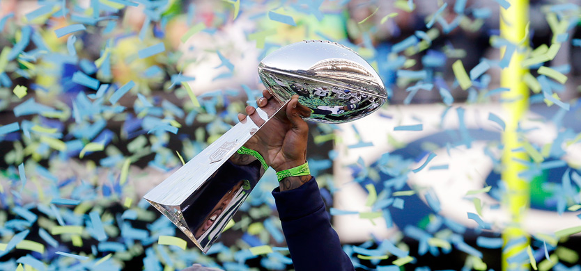 A Seattle Seahawks player holds the Vince Lombardi Trophy aloft as confetti drops around it at a rally following a parade for the Super Bowl champions Wednesday, Feb. 5, 2014, in Seattle. The Seahawks beat the Denver Broncos 43-8 on Sunday. (AP Photo/Elaine Thompson) 